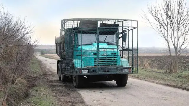Бірюзовий КрАЗ «у клітці»: біля фронту помітили будівельну машину з антидроновим захистом