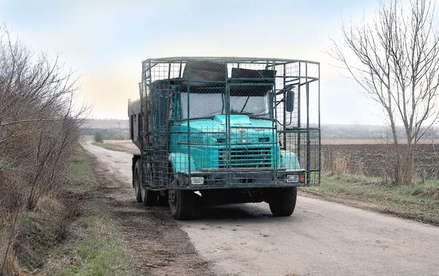 Бірюзовий КрАЗ «у клітці»: біля фронту помітили будівельну машину з антидроновим захистом